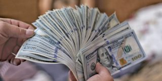Trump's 10% tariff hits US laptop prices, but Apple absorbing cost for now | A hand holding $100 bills