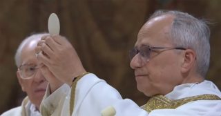An Apple Watch-wearing Pope Leo XIV holds in a host during his first official mass