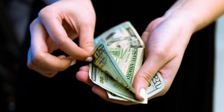 Are you eligible for a share of Apple's $250M new Siri settlement? | Photo shows hands counting out $20 bills