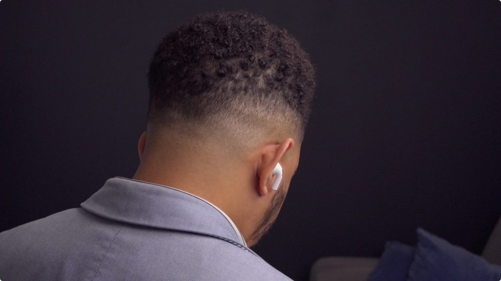 AirPods 4 in ear behind subject