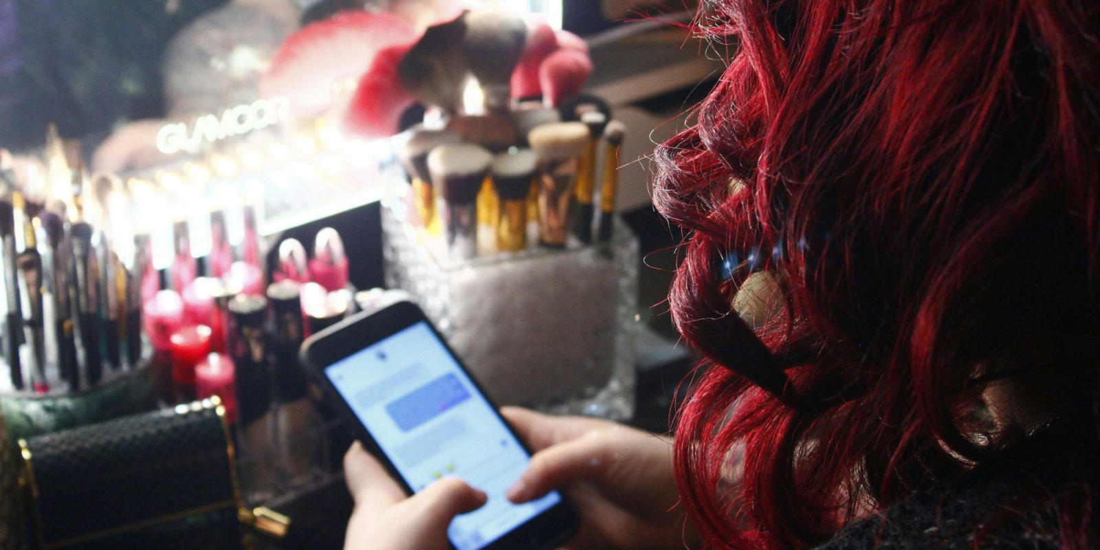 UK carrier Three supporting RCS for iPhone users | Woman using iMessage at a make-up table