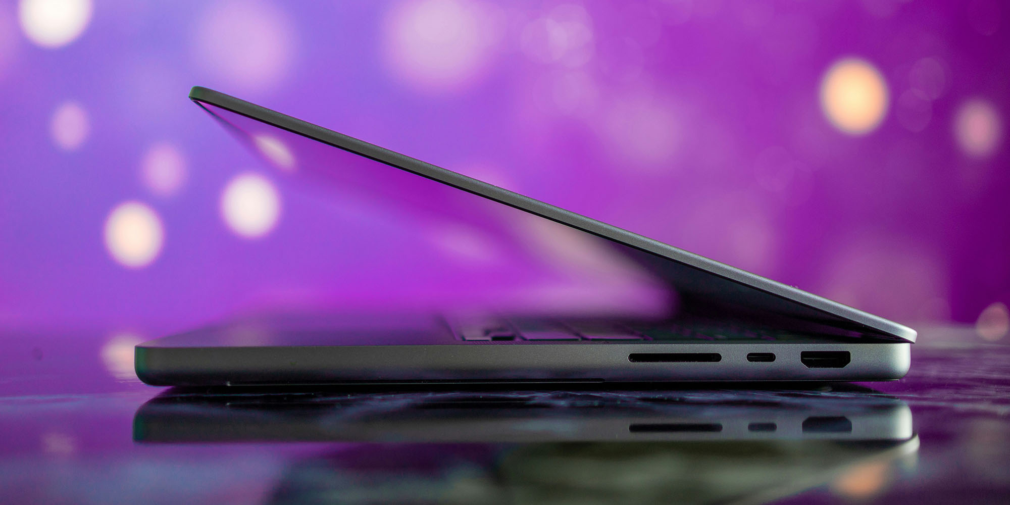 The Cost-Friendly MacBook Upgrade Plan That’s Built for Power Users | Half-open MacBook Pro from the side against a purple background