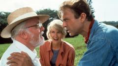 Sam Neill in Jurassic Park with his hand on co-star Richard Attenborough's arm as Laura Dern looks on and smiles