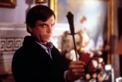 Sam Neill in The Omen holding a crucifix
