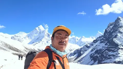 Jangbu Sherpa Jangbu Sherpa of the Chhukung Village with mountains in the Everest region on the background