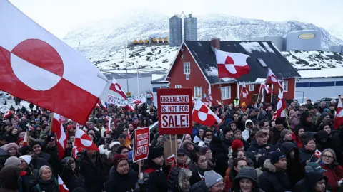 Getty Images eople hold Greenlandic flags and placards as they gather by the United States Consulate to march in protest against U.S. President Donald Trump and his announced intent to acquire Greenland on January 17, 2026 in Nuuk, Greenland. 