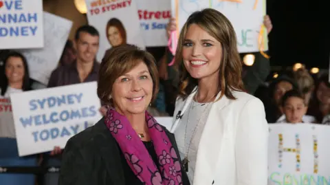 NBC / Reuters Nancy Guthrie, the 84-year-old mother of US. journalist and television host Savannah Guthrie, who went missing from her home in Tucson, poses with her daughter in front of people carrying signs welcoming them to Sydney, Australia in 2015. 