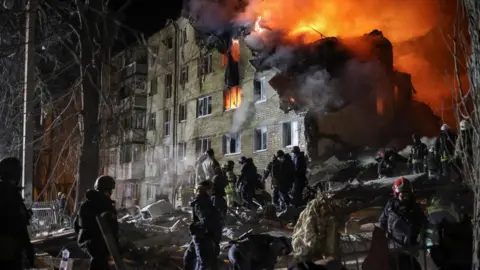 Reuters Rescuers work at the site of the apartment building hit by a Russian missile strike in Kharkiv