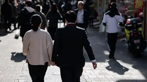 Getty Images A couple walks through a shopping street on February 06, 2026 in Tokyo, Japan.