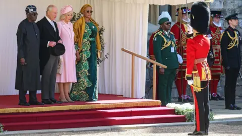 Getty Images King Charles, President Tinubu, Queen Camilla and First Lady Oluremi Tinubu with other uniformed figures outside Windsor Castle