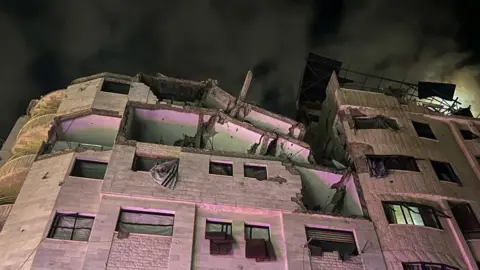 Reuters A block of flats damaged by an air strike pictured at night