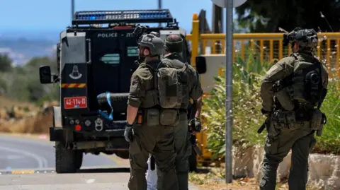 Reuters Three Israeli emergency personnel at the scene of the shooting with a police truck in front of them