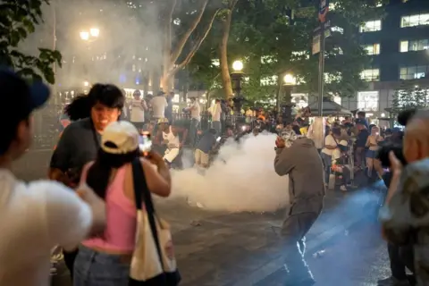 Reuters People run away in different directions from what appears to be a flare or firework that's produced a cloud of smoke in Manhattan, New York City at night time.