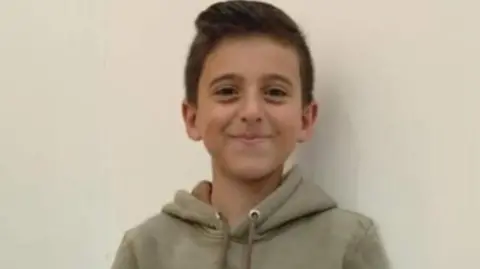 BBC Jawad wears a grey hoodie and smiles for the camera
