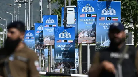 AFP via Getty Images Security personnel stand guard at a security checkpost along a road temporarily closed near the Serena Hotel at the Red Zone area in Islamabad on April 20, 2026.