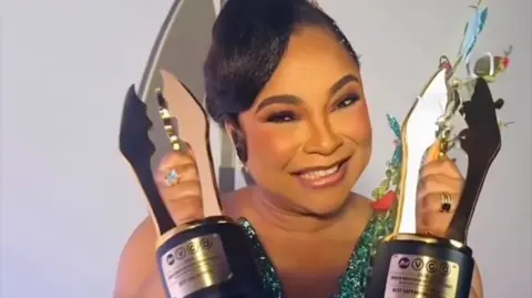 Ibrahim Suleiman Linda Ejiofor, in a shining blue dress, holds her trophies.
