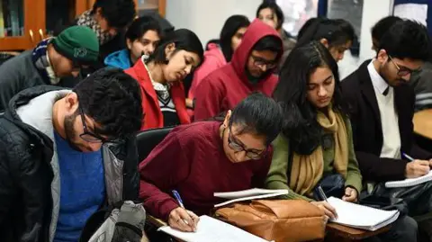 Getty Images Students wearing woolens - jackets, scarves and sweaters - take notes in a class at the Ramjas College of Delhi University