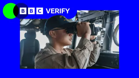 US Central Command A US Navy sailor is seen holding a pair of binoculars to their eyes on the bridge of a warship in an image published by US Central Command