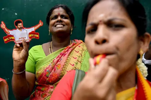 AFP via Getty Images Tamilaga Vettri Kazhagam (TVK) party members blow a whistle (party symbol) and hold a cut-out of Indian actor and party president C. Joseph Vijay to celebrate during vote counting for the Tamil Nadu Legislative Assembly elections, at the party headquarters in Chennai on May 4, 2026. 