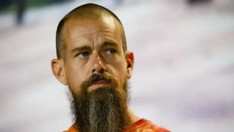 Bloomberg via Getty Images Close up of Jack Dorsey looking thoughtfully upwards. He has a close shaved head and a bushy long beard. There is snow in the background