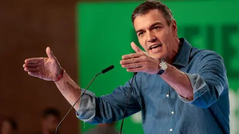 NurPhoto via Getty Images File pic showing Spain's PM wearing a denim shirt in front of a green background