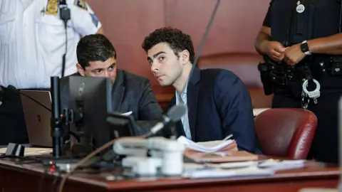 Getty Images Luigi Mangione speaks with his lawyer during a court hearing in New York on 18 May 2026.