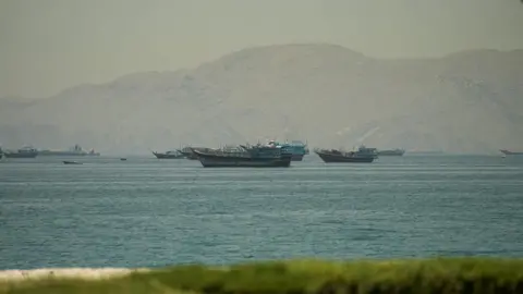 Reuters Boats in the Strait of Hormuz, seen from Oman, with mountains behind