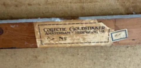 Arthur Brand A worn brown sticker on the back of the Portrait of a Young Girl's frame, it reads 'Collectie Goudstikker' and is partially torn at its edges. 