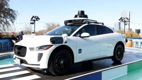 Getty Images A white Waymo taxi in the day on a road in the US
