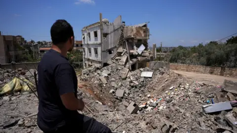 Reuters A man looks at the remains of a building destroyed by an Israeli strike in Kfar Sir, in Nabatieh district, southern Lebanon (16 June 2026)