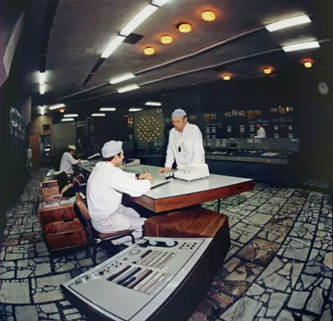 Sovfoto/Universal Images Group/Shutterstock Archive colour image showing two workers in white suits and hats at a unit control desk at the Chernobyl Nuclear Power Plant in April 1983.