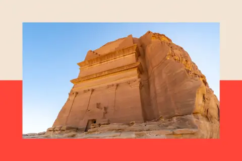 Getty Images A large yellow rock monument looms against a bright blue sky