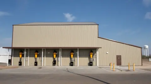 US Department of Agriculture A new sterile fly facility. Its a building with yellow dispensers on the side