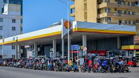 Getty Images Motorists wait in a queue to refuel their vehicles at a filling station in Wellawatte on the outskirts of Colombo