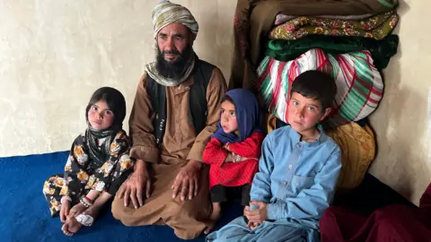 Imogen Anderson/BBC Abdul Rashid Azimi sits on the floor looking visibly sad with three of his children. 