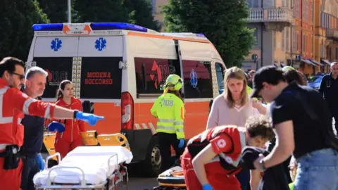 EPA Paramedics in red uniforms attend to injured people, an ambulance can bee seen as well as a stretcher in addition to civilians