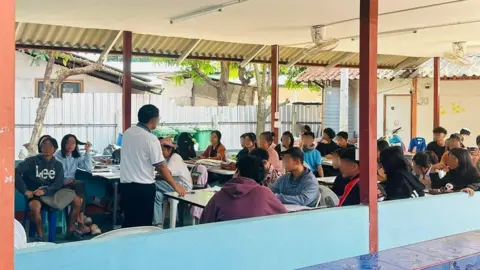 Supplied by student Dozens of students sitting in a classroom, while a man stands at the front