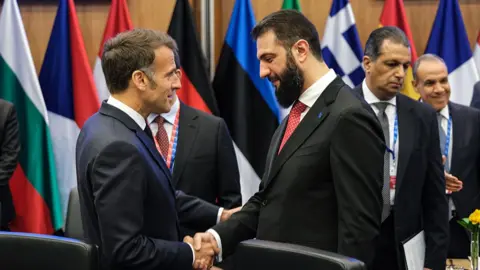 Getty Images French President Emmanuel Macron greets Syrian President Ahmed al-Sharaa