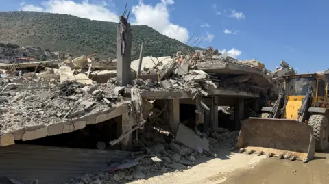 BBC An excavator stands next to a collapsed building following overnight Israeli strikes in Mashghara, south-eastern Lebanon (26 May 2026)