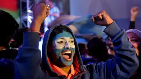 NurPhoto via Getty Images A fan of the Argentina football team raises his fists in the air while watching the Argentina v France final at a viewing party in Kolkata, India