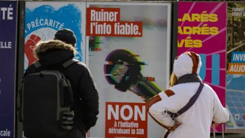 Reuters People in Geneva look at a poster urging people to vote 