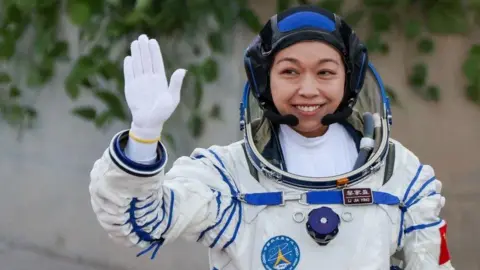 Reuters Li Jiaying, Hong Kong's first astronaut, waves while wearing a full white space suit