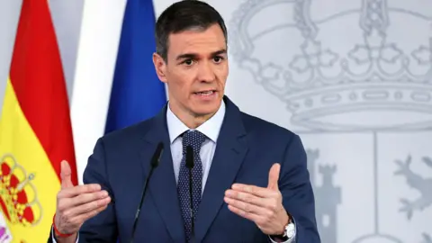 Getty Images Pedro Sanchez gesturing with handsand short greying brown hair, wears a suit and tie as he speaks during a press conference