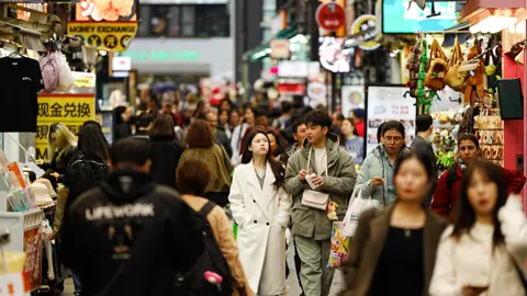 People walk down a busy shopping street.