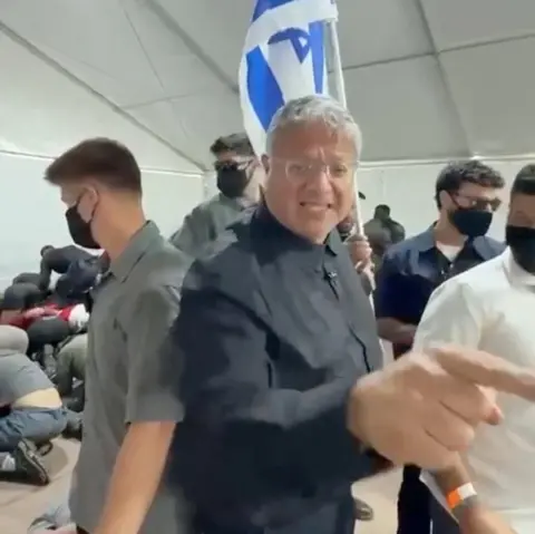 Office Of Itamar Ben Gvir/Handout via Reuters Israeli National Security Minister gestures in front of an Israeli flag while touring a facility in the Israeli port of Ashdod where pro-Palestinian activists from a Gaza-bound flotilla are being detained (20 May 2026)