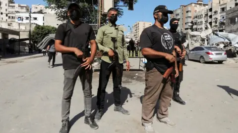 Reuters Four Hamas policeman stand guard on a street in Gaza (11/10/25)