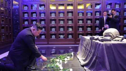 KCNA Kim Jong Un lays white flowers inside the columbarium, which contains rows of urns inside 