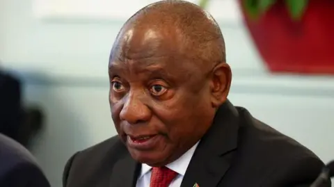 Reuters A close-up of President Cyril Ramaphosa wearing a black suit, white shirt and a red-dotted tie.