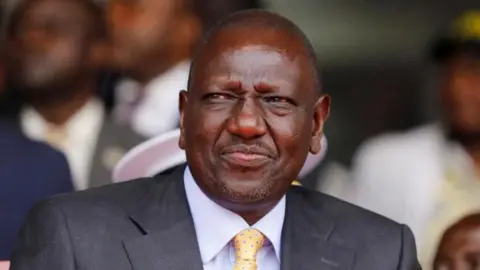 Reuters A close-up of President William Ruto in a grey suit, blue shirt and dotted tie during a past public event in Nairobi.
