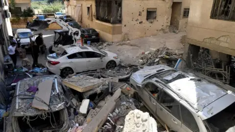 EPA A number of cars on a street between buildings; they show damage caused by falling debris